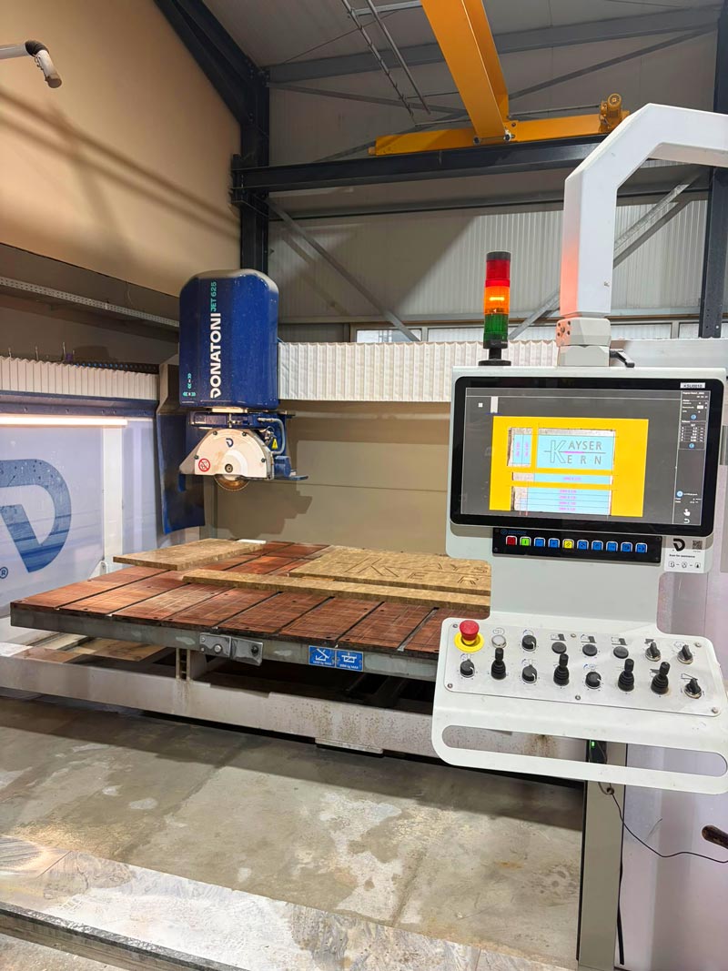 CNC-Brückensäge Donatoni JET 625 bei Kayser & Kern mit Sägekopf, Natursteinplatten auf dem Arbeitstisch und seitlichem Bedienpult.